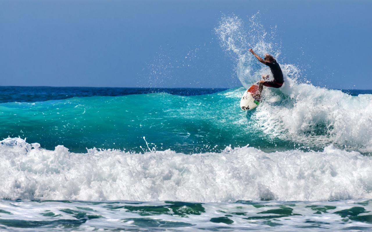 surfista cavalca un'onda con la sua tavola (bassa california, messico)