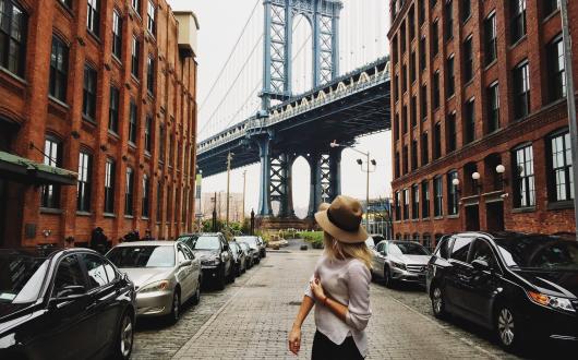 ragazza di fronte allo scorcio del mahattan bridge visto dal quartiere di dumbo a brooklyn (new york, stati uniti)