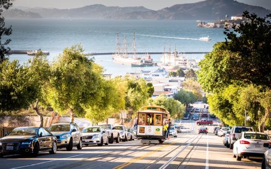 cable car lungo strada in salita e baia di san francisco (california, stati uniti)