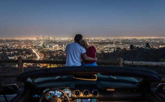 coppia abbracciata ammira le luci di los angeles di sera (california, stati uniti)