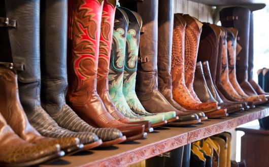 stivali da cowboy allineati su una mensola in un negozio (texas, stati uniti)