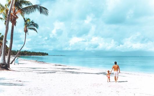 papà e figlia camminano su una spiaggia bianca di santo domingo (repubblica dominicana, caraibi)