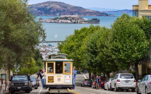 cable car lungo strada in salita e baia di san francisco (california, stati uniti)