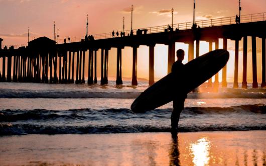 surfista su una spiaggia della california al tramonto (california, stati uniti)