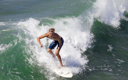 surfista cavalca un'onda con la sua tavola a venice beach (california, stati uniti)