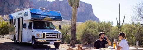 camper in area sosta con cactus e tavolo da campeggio