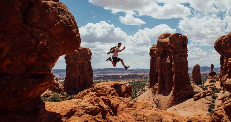 ragazzo salta tra gli archi all'arches national park (utah, stati uniti)