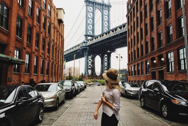 ragazza di fronte allo scorcio del mahattan bridge visto dal quartiere di dumbo a brooklyn (new york, stati uniti)