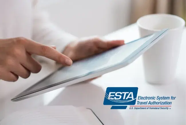 Mani che sfogliano un passaporto con sullo sfondo il logo ufficiale ESTA – Electronic System for Travel Authorization del Dipartimento della Sicurezza Nazionale degli Stati Uniti